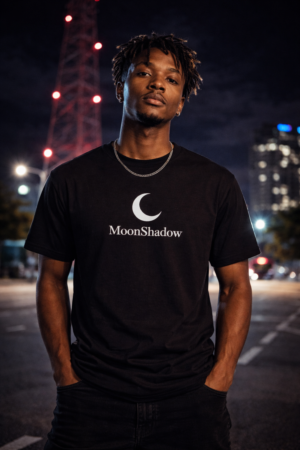 Person wearing a black t-shirt with 'MoonShadow' logo at night in an urban setting