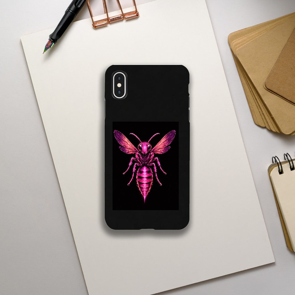 Phone case with pink insect design on a black background, placed on a light gray surface with stationery items.