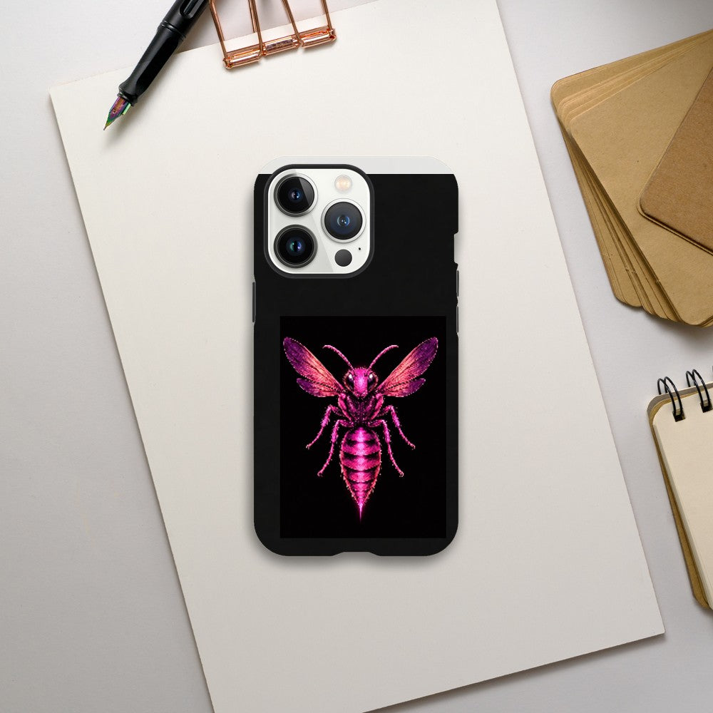 Phone case with pink insect design on a black background, placed on a light gray surface with stationery items.